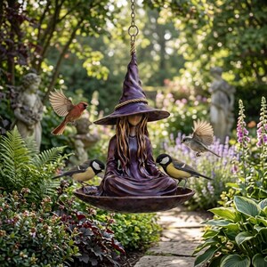 May include: A bronze-colored, hanging bird feeder shaped like a seated witch with a pointed hat. The witch is surrounded by birds in a lush garden setting. The feeder has a wide, shallow bowl for birdseed.