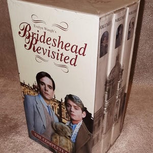 Könnte beinhalten: Ein Box-Set der kompletten Serie Brideshead Revisited von Evelyn Waugh. Das Frontcover zeigt zwei Personen, von denen eine einen Teddybären hält, vor einem Gebäude. Die Seite zeigt drei Bände mit architektonischen Abbildungen.
