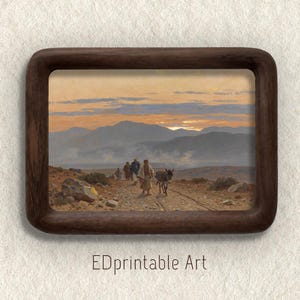 Puede incluir: Impresión enmarcada de un paisaje con figuras caminando por un camino, acompañadas de un burro. La obra presenta un atardecer sobre montañas distantes. El marco es marrón oscuro, con el texto "EDPrintable Art" en la parte inferior.
