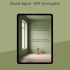 May include: A digital ebook displayed on a tablet. The ebook cover features a room with a window, a small wooden stool, and text in Spanish: "Reset de 7 días para recuperar energía cuando estás agotado."