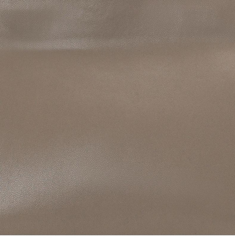 May include: A close-up shot of a textured, taupe-colored surface. The surface has a subtle, grainy texture, and the color is a muted, neutral tone. The lighting is even, highlighting the surface's details. The overall impression is of a smooth, yet tactile material.