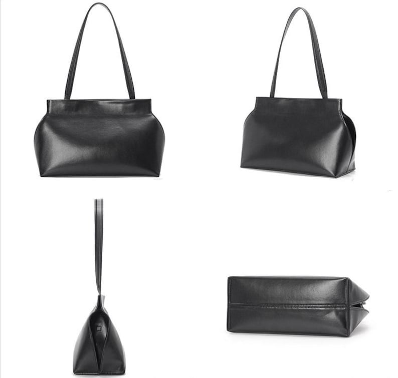 May include: A black leather tote bag with a rectangular body and curved sides. The bag has two long, thin handles and a structured design. The leather appears smooth and has a slight sheen. The bag is shown from multiple angles.