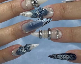 Uñas postizas estilo cyberpunk azul con forma de aguja / Flor cromada 3D y detalle de anillo plateado.