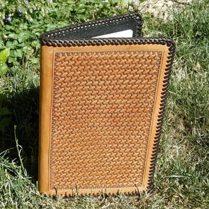 May include: A brown leather journal with a black leather border and a woven pattern on the front cover.
