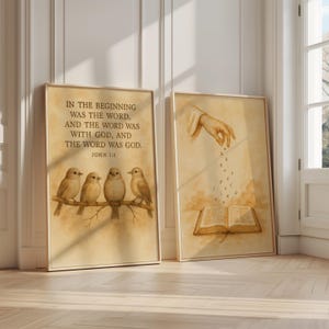 May include: Two framed art prints with a vintage aesthetic. One features the text "IN THE BEGINNING WAS THE WORD..." and four birds on a branch. The other depicts a hand scattering letters over an open book. Both are in neutral tones.
