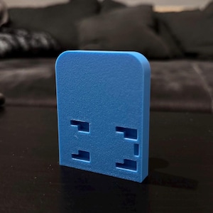 Op de afbeelding: Een helderblauw, rechthoekig object met een textuur en afgeronde hoeken. Het object heeft vier rechthoekige uitsparingen aan de voorkant. Het item is waarschijnlijk een decoratief of functioneel stuk.