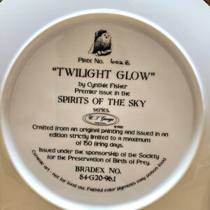 May include: A white ceramic plate with the text "TWILIGHT GLOW" and an illustration of an owl. The plate is part of the "SPIRITS OF THE SKY" series by Cynthia Fisher. It was issued under the sponsorship of the Society for the Preservation of Birds of Prey.