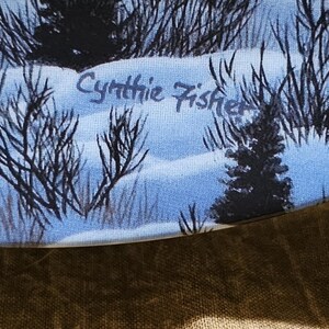 May include: A winter landscape painting featuring snow-covered ground, dark bare trees, and a small evergreen tree. The artist's signature, "Cynthia Fisher," is visible in the upper center. The color palette includes shades of blue, white, and black.