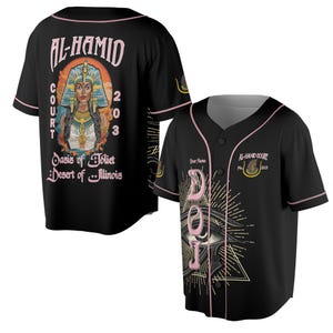 Könnte beinhalten: Schwarzes Baseball-Trikot mit rosa Besatz und Knopfverschluss. Die Vorderseite zeigt eine Augengrafik und die Buchstaben "DOJ". Auf der Rückseite befindet sich eine Grafik einer Frau und der Text "AL-HAMID COURT 203 Oasis of Joliet Desert of Illinois".
