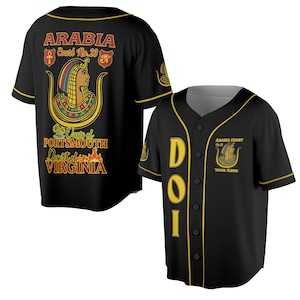Op de afbeelding: Zwart honkbalshirt met gouden rand en knopen. De voorkant heeft de letters "DOI" in goud. De achterkant toont "ARABIA Court No. 23" met een Egyptisch thema en de tekst "Oasis of Portsmouth Desert of Virginia."