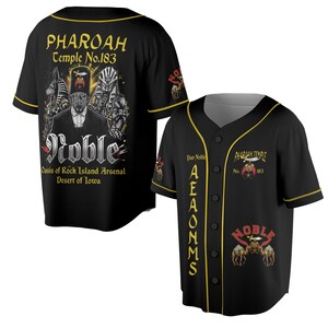 May include: A black baseball jersey with gold trim, featuring graphic prints of Egyptian-themed figures, camels, and text including PHAROAH Temple No.183, Noble, Oasis of Rock Island Arsenal, Desert of Iowa, and AEAONMS on the front and back.