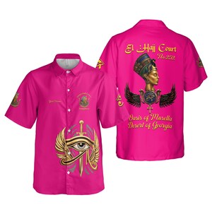 Peut inclure: Une chemise rose vif à manches courtes. Elle présente des motifs graphiques dorés et argentés, dont un symbole d'œil ailé et du texte indiquant "El Haji Court No. 252" et "Oasis of Musella Desert of Georgia".