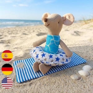 Könnte beinhalten: Ein beiges Stoffmaus-Plüschtier in einem leuchtend blauen Badeanzug mit weißem Wellenmuster. Die Maus sitzt in einem weißen aufblasbaren Schwimmring mit blau-grauem Sternenmuster, der auf einer blau-weiß gestreiften Stoffmatte platziert ist.