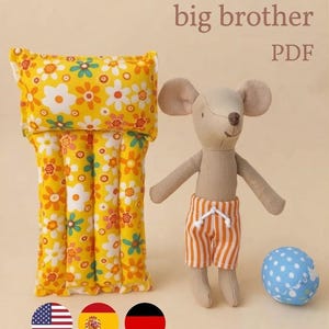 May include: A beige fabric mouse doll wearing orange and white striped shorts, standing next to a yellow floral patterned sleeping bag and a small blue polka dot ball. The text "Clothing set big brother PDF" is visible at the top of the image.