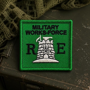 May include: A square green embroidered patch featuring the black text MILITARY WORKS-FORCE at the top. In the center, a white stone tower graphic is flanked by the black letters R and E, with a small white tool icon positioned above the tower.