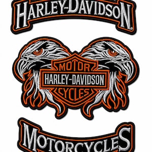 May include: Three Harley-Davidson patches with black borders and white embroidered text. The top patch reads "HARLEY-DAVIDSON" in a curved design. The center patch features two eagle heads flanking a logo with "MOTOR HARLEY-DAVIDSON CYCLES". The bottom patch reads "MOTORCYCLES".