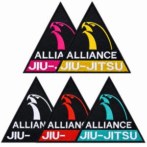 Może przedstawiać: Pięć trójkątnych haftowanych naszywek z czarnym tłem. Każda z nich zawiera stylizowaną ikonę głowy ptaka oraz napis ALLIANCE JIU-JITSU. Ikony ptaków i dolne paski z tekstem występują w kolorach różowym, żółtym, białym, czerwonym i turkusowym.