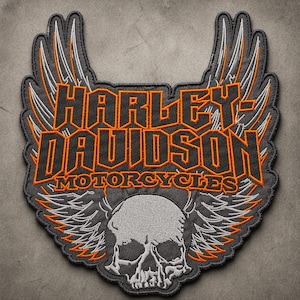 May include: Embroidered Harley-Davidson Motorcycles patch featuring a skull with wings. The patch has a gray background with orange and white accents. The Harley-Davidson logo is prominently displayed in orange.