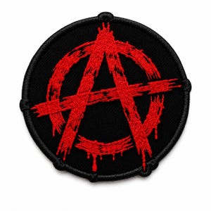 May include: A circular embroidered patch featuring a black background with a red anarchy symbol. The symbol is rendered in a distressed, brushstroke style with dripping paint effects at the bottom edges. The patch has a thick black stitched border.
