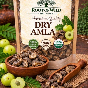 以下が含まれることがあります： 木のアートアイコンが描かれたラベル付きのRoot of Wild Organics Premium Quality Dry Amlaのスタンドパウチ。パウチには濃い茶色の乾燥アムラが入っています。乾燥アムラが入った木製のボウルと木製のスクープが、新鮮な緑色のアムラの横に置かれています。