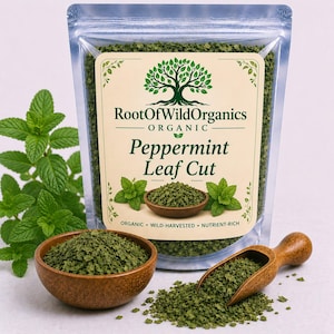May include: A clear bag of organic peppermint leaf cut with the brand name "Root Of Wild Organics". A wooden bowl and scoop are filled with the green leaves. Fresh mint sprigs are in the background.