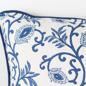 May include: A white pillow with a blue floral pattern. The pillow has a blue border.