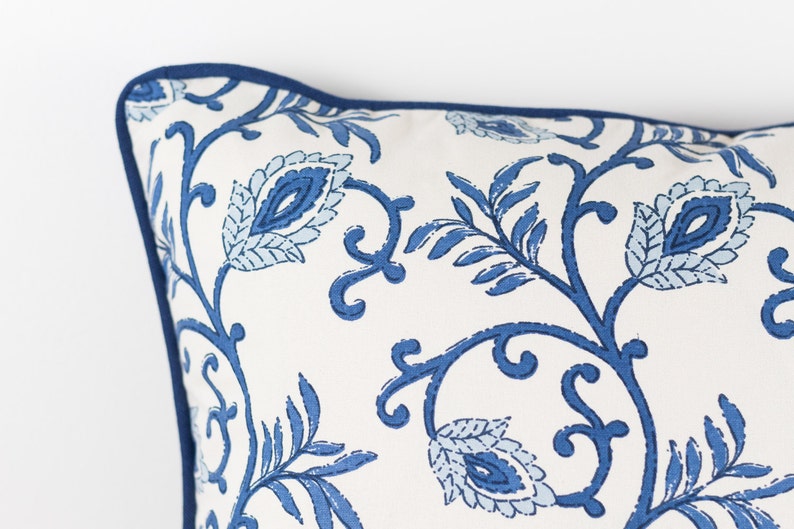 May include: A white pillow with a blue floral pattern. The pillow has a blue border.