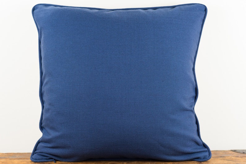 May include: A solid blue throw pillow with a simple design. The pillow is made of a soft, textured fabric.