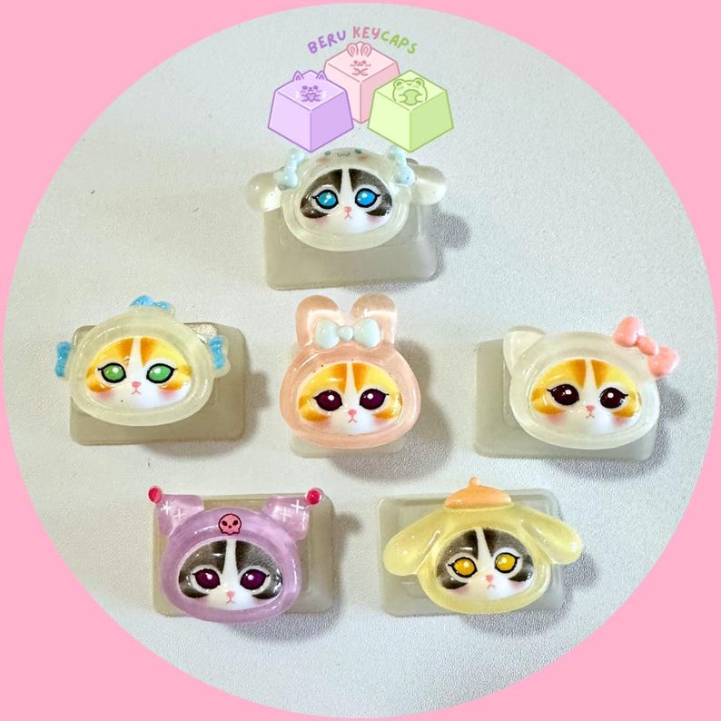 Pode incluir: Uma cole&ccedil;&atilde;o de keycaps com tema de gato em v&aacute;rios designs. Cada keycap apresenta um rosto de gato com diferentes roupas, incluindo um coelho, um urso e um gato com chifres. As keycaps s&atilde;o em uma variedade de cores, incluindo rosa, amarelo e roxo.