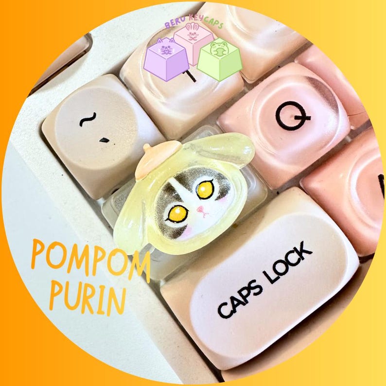 Pode incluir: Uma tecla de teclado personalizada com um personagem de desenho animado em uma roupa amarela. A tecla est&aacute; em um teclado branco com outras teclas em tons de branco e rosa. O texto "POMPOM PURIN" e "CAPS LOCK" s&atilde;o vis&iacute;veis.