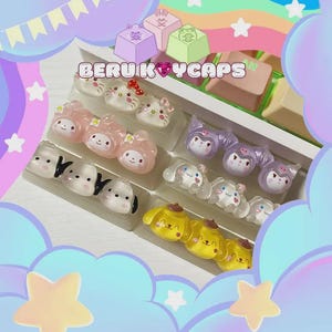 May include: A selection of keycaps with cartoon character designs, presented in a white tray. The keycaps showcase characters like cats and dogs, in various colours. The text "BERU KEYCAPS" is displayed on the tray.