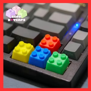 Peut inclure: Gros plan sur un clavier d'ordinateur avec des touches colorées en forme de briques de construction. Les touches sont jaunes, bleues, rouges et vertes. Le texte "BERU KEYCAPS" est visible en haut à gauche.