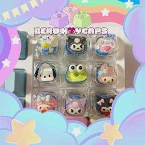 May include: A set of nine colorful keyboard keycaps featuring various cartoon characters. The keycaps are in clear plastic cases with blue trim. The text "BERU KEYCAPS" is displayed above the keycaps. The background is a pastel rainbow.