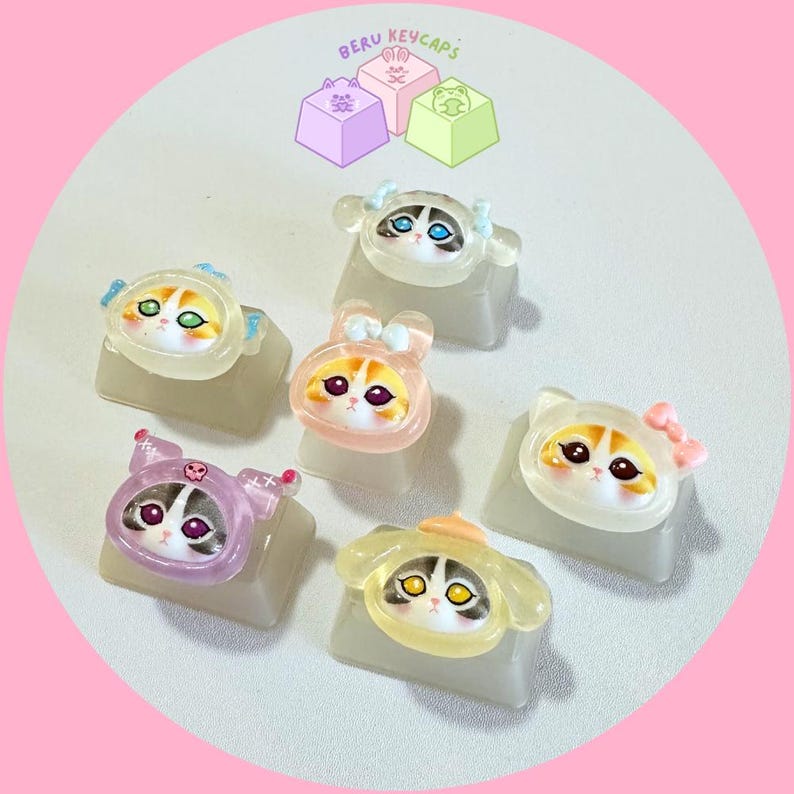 Pode incluir: Uma cole&ccedil;&atilde;o de teclas de teclado com tema de gato, cada uma com um design &uacute;nico e v&aacute;rias cores e acess&oacute;rios. As teclas transl&uacute;cidas s&atilde;o exibidas em uma superf&iacute;cie branca. O texto "BERU KEYCAPS" &eacute; vis&iacute;vel na parte superior.