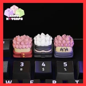 May include: Three custom keycaps with anime-style character designs. The keycaps feature pink, white, and purple hair, and are set on a black keyboard. The brand name "BERU KEYCAPS" is visible in the top left corner.