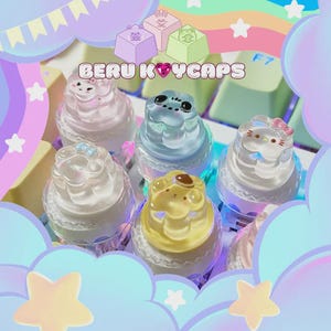 May include: A collection of colorful, decorative keycaps with various cute character designs, including a cat, frog, and bear. The keycaps are translucent and sit on a keyboard, with the text "BERU KEYCAPS" visible.