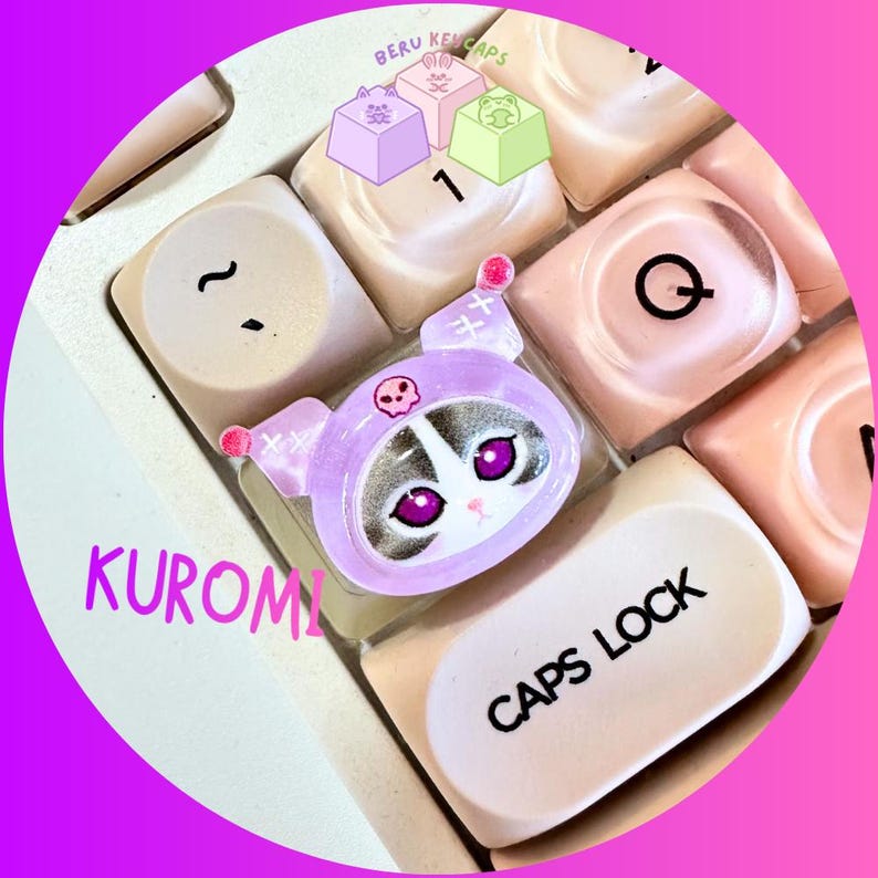 Pode incluir: Uma tecla personalizada com um design Kuromi, com um capuz roxo e um detalhe de caveira. A tecla est&aacute; colocada num teclado com outras teclas brancas e rosa. A palavra "KUROMI" est&aacute; escrita em rosa.
