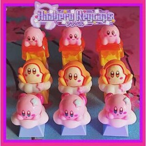 May include: A collection of pink and orange keycaps featuring a cartoon character with large eyes and a smiling expression. The keycaps are arranged in three rows of three, with a logo at the top that reads "Ahaberu Keycaps" in English and Japanese.