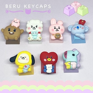 Puede incluir: Una colección de coloridas teclas decorativas con personajes de dibujos animados. Las teclas tienen varias formas y colores, incluyendo marrón, blanco, rosa, azul, amarillo y rojo. El texto "BERU KEYCAPS" está en la parte superior de la imagen.