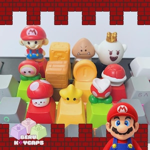 May include: A collection of colorful keycaps featuring characters and elements from the Super Mario video game series. Includes Mario, Goomba, Boo, and other iconic designs. The keycaps are arranged on a keyboard, with a brick-patterned border.