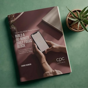 Könnte beinhalten: Ein Buch mit dem Titel "Build a 90-Minute Daily Focus Block" mit dem Text "The 14-Day ADHD Phone Pull Reset". Ein Smartphone wird über dem Buch gehalten. Das Buch liegt auf einer weinroten Oberfläche mit grünem Hintergrund. Eine Topfpflanze befindet sich in der oberen rechten Ecke.