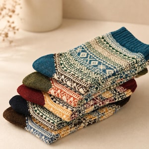 May include: A stack of five pairs of knit socks featuring intricate geometric patterns in various colours including blue, green, red, yellow, and brown. Each pair has a solid-coloured toe and heel section with a ribbed cuff at the top.