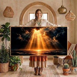 May include: A rectangular wall art print featuring a dramatic seascape at sunset. Golden sunbeams pierce through dark, heavy clouds, illuminating the turbulent ocean waves below. The artwork is presented in a thin, light-colored wooden frame.