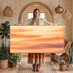 Könnte beinhalten: Ein rechteckiges Landschaftsgemälde mit einem lebendigen Sonnenuntergang, der horizontale Bänder aus orangefarbenen, pfirsichfarbenen und sanften violetten Wolken zeigt. Das Kunstwerk ist in hellem Holz gerahmt und stellt einen heiteren Himmel dar.