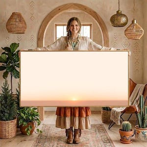 May include: A large rectangular framed wall art piece featuring a minimalist sunset landscape with a soft gradient of pale orange and peach hues. The artwork is encased in a thin, light-toned wooden frame, presenting a clean and expansive horizon line.