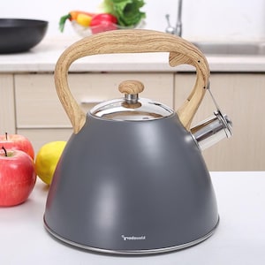 May include: A gray stovetop kettle with a wooden handle and lid knob. The kettle has a stainless steel spout and a shiny, silver lid. The handle and knob are made of light-colored wood. The kettle is sitting on a white surface.
