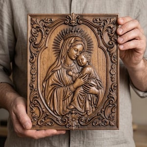 May include: A rectangular wooden wall plaque featuring a detailed relief carving of the Virgin Mary holding the infant Jesus. The central figures are enclosed in an oval frame decorated with intricate floral and scrollwork patterns in dark wood.