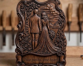 May include: A dark brown wooden plaque featuring a relief carving of a couple standing together. The scene includes a tree, roses, and a landscape with clouds. At the bottom, a scroll design contains the engraved text: Two paths, one heart.
