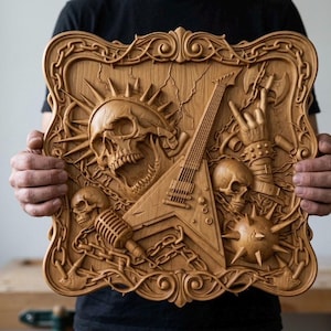 May include: A wooden relief carving featuring a skull with sun rays, a guitar, and other rock and roll themed elements. The artwork is framed with an ornate border and is held by a person.