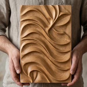 May include: A rectangular wooden panel with a carved, flowing wave design. The panel is held by a person and features a natural wood grain finish. The carved relief creates a textured, three-dimensional effect, suitable for wall decor.